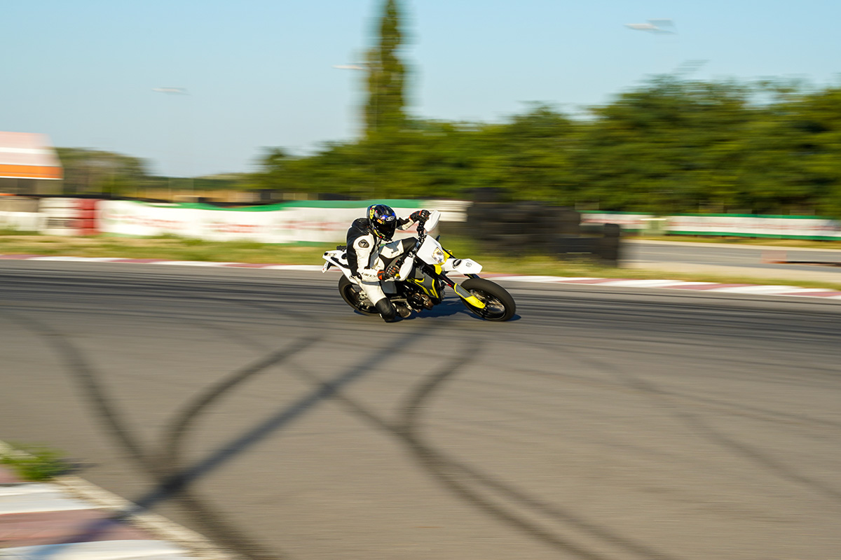 Motocicletă neagră cu pilot în echipament roșu și galben